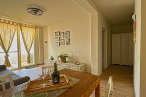 A dining area with a table set for two, a bottle of wine, and a tray. There are two chairs, a potted plant, and a cabinet with framed pictures on the wall. - Ocean View Retreat with Rooftop Terrace & Beach (Sal Rei)