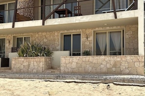 A two-story building with a stone facade, large windows, and outdoor seating areas with plants. - Ocean View Retreat with Rooftop Terrace & Beach (Sal Rei)