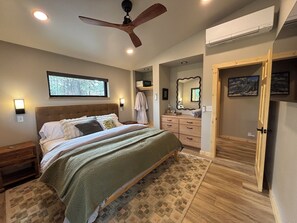 A bedroom with a bed, bedside tables, a dresser, a mirror, and a ceiling fan. - Mountain-modern vacation rental with Full Kitchen, King Bed, Fireplace, Hot Tub (Winthrop)
