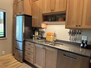 A kitchen with wooden cabinets, stainless steel appliances, a built-in knife rack, and a window with a view. - Mountain-modern vacation rental with Full Kitchen, King Bed, Fireplace, Hot Tub (Winthrop)