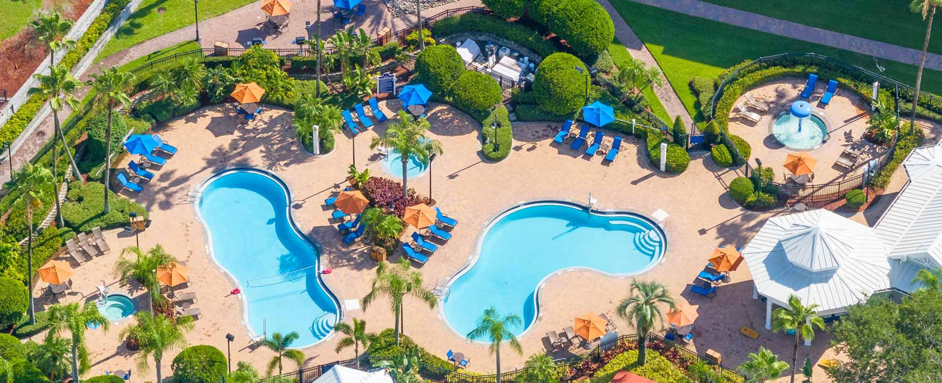 Un resort con due ampie piscine, lettini e palme.