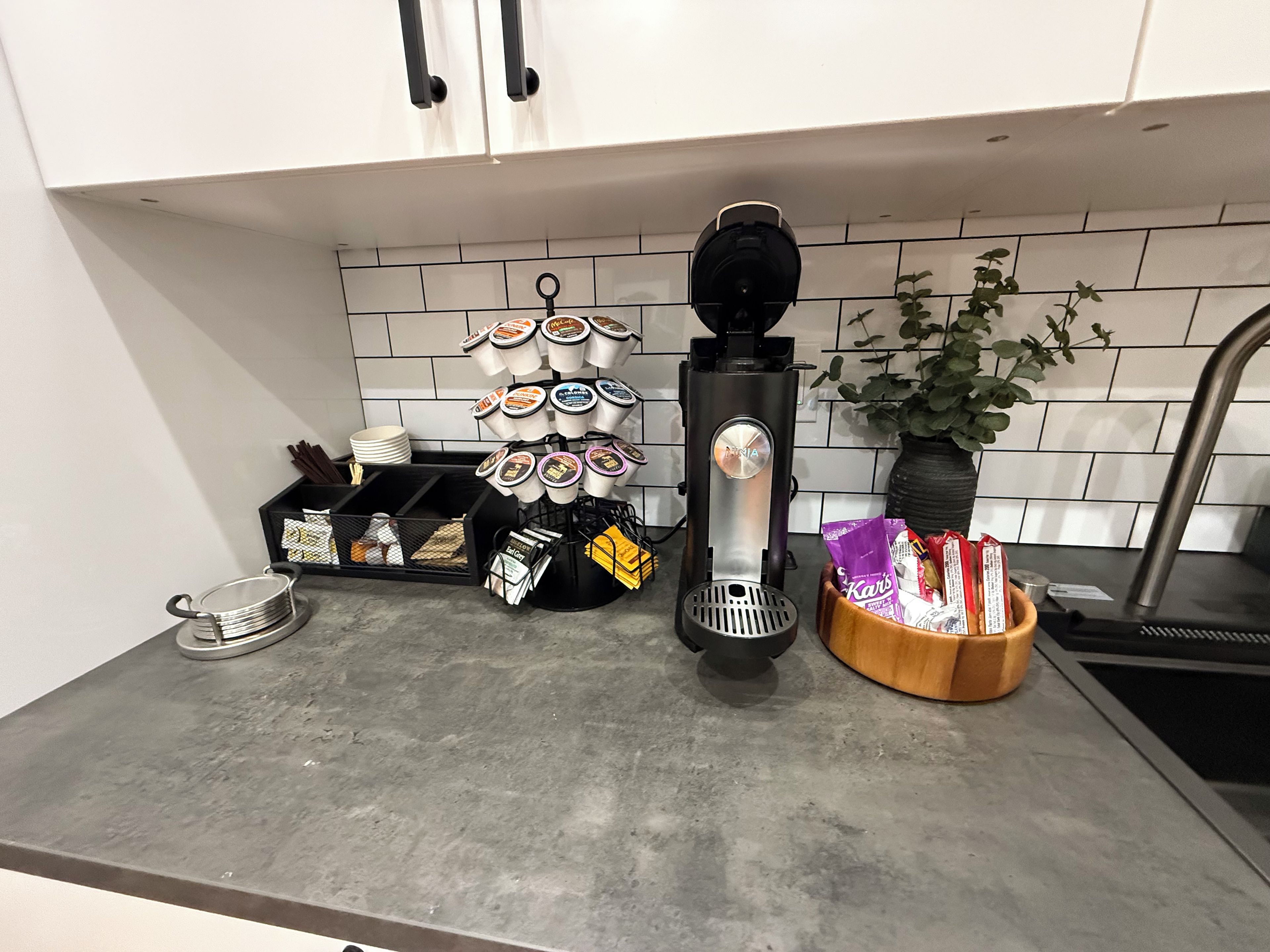 Een aanrecht met een koffieapparaat, een plant en diverse keukenspullen.