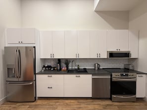 Une cuisine moderne avec des armoires blanches, des appareils en acier inoxydable et un comptoir noir.