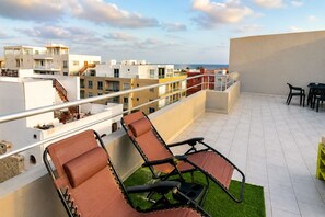 A rooftop terrace with sun loungers, a small table, and chairs, overlooking a cityscape. - 2 apartments for up to 8 guests in Estoril beach (Sal Rei)