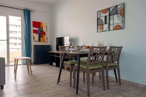 A dining area with a table set for four, a television, and a colorful abstract painting on the wall. - 2 apartments for up to 8 guests in Estoril beach (Sal Rei)