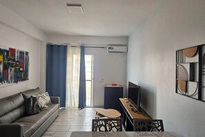 A modern living room with a sofa, a dining table, and a TV. - 2 apartments for up to 8 guests in Estoril beach (Sal Rei)