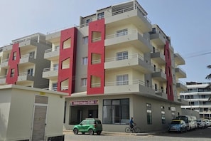 A multi-story residential building with balconies and a sign that reads 'TUDO PARA CASA'. - 2 apartments for up to 8 guests in Estoril beach (Sal Rei)