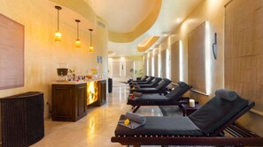 Un espace bien-être comprenant des fauteuils de massage, un comptoir d’accueil et un appareil de massage fixé au mur.