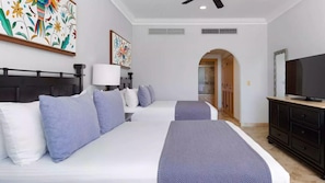 Ein Hotelzimmer mit zwei Betten, einem Fernseher, einer Lampe und Kunstwerken an den Wänden.