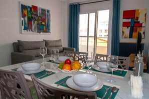 A dining area with a table set for two, fruit on the table, and a view of the outside. - 2 apartments for up to 10 guests in Estoril beach (Sal Rei)