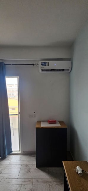 Ein Zimmer mit einer Schiebetür, einem kleinen Tisch mit einem roten Gegenstand und einer an der Wand befestigten Klimaanlage.