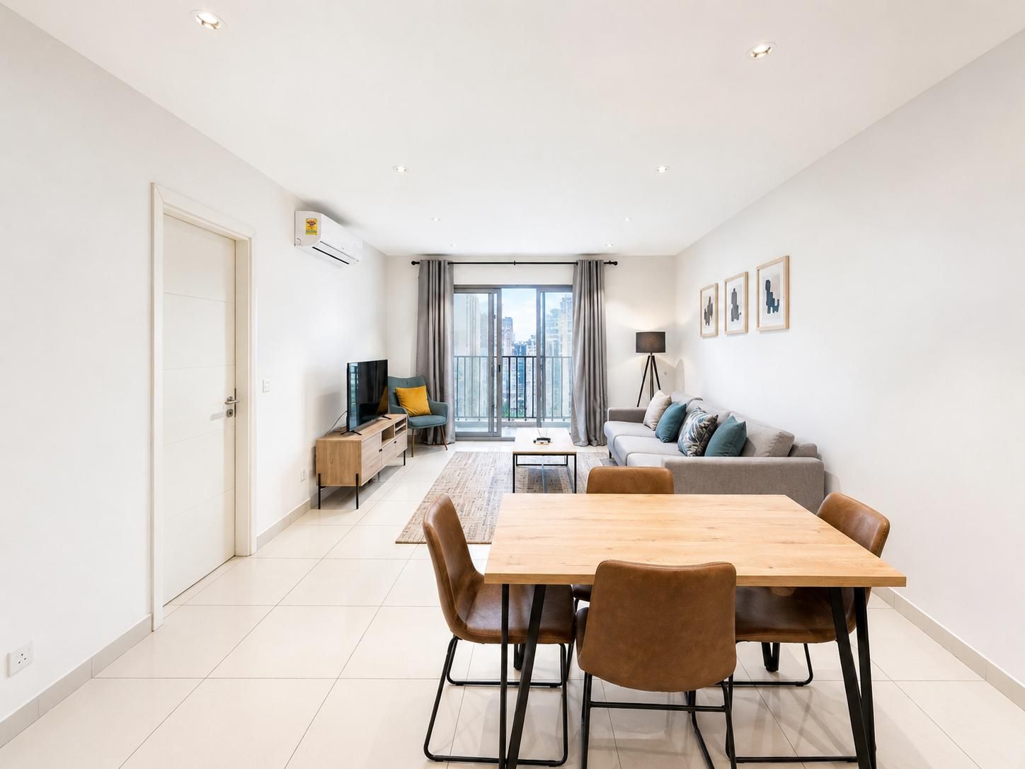 Un salon moderne comprenant un coin repas, un ensemble de canapés, un téléviseur et un balcon avec vue sur la ville.