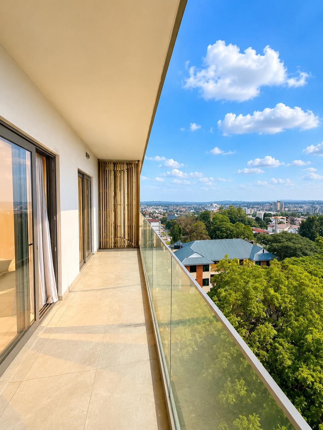 Un balcon avec vue sur la ville, des portes vitrées et un sol carrelé.