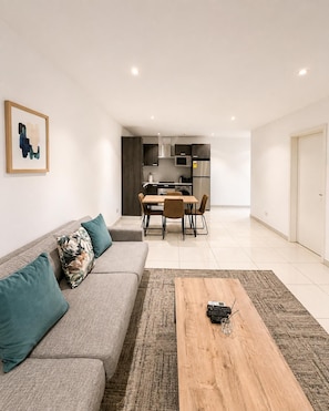 Una sala de estar moderna con sofá, una mesa de centro y una zona de comedor con sillas y una mesa.
