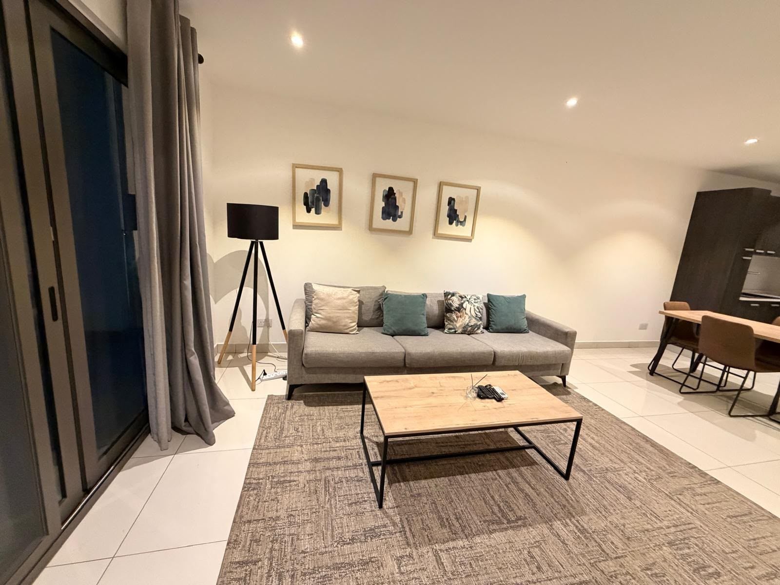 Un salon moderne avec un canapé, une table basse et un lampadaire.