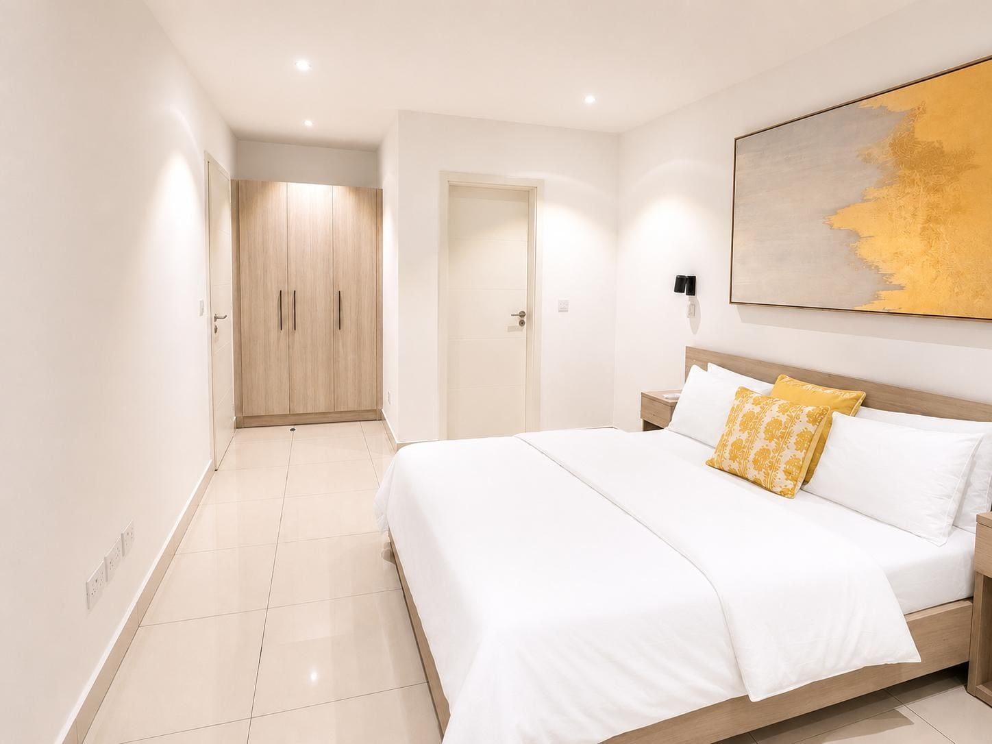 Une chambre à coucher moderne avec un grand lit, une armoire et un tableau au mur.