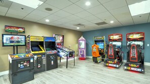 Eine Spielhalle mit verschiedenen Renn- und Arcade-Spielen, darunter ein Pac-Man-Automaten und ein NASCAR-Rennspiel.