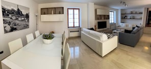A modern living space with a dining area, a sofa, a television, and a bookshelf. - Apartment at the Port (Malcesine)