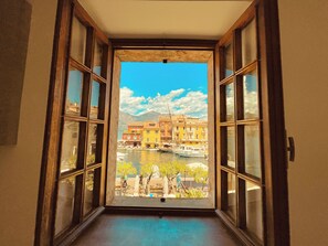 An open doorway leading to a view of a waterfront with buildings and boats. - Apartment at the Port (Malcesine)