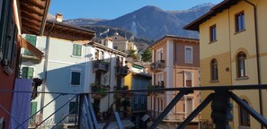 A narrow street with buildings on either side, a mountain in the background, and a clear sky. - Apartment at the Port (Malcesine)