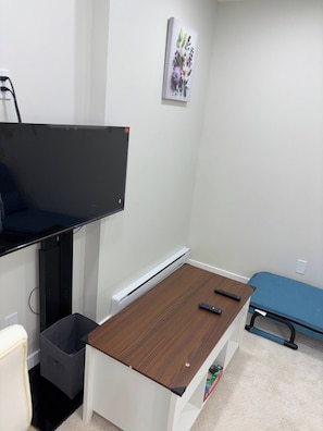 Una habitación con escritorio, silla, cama, calefactor y televisor de pared.