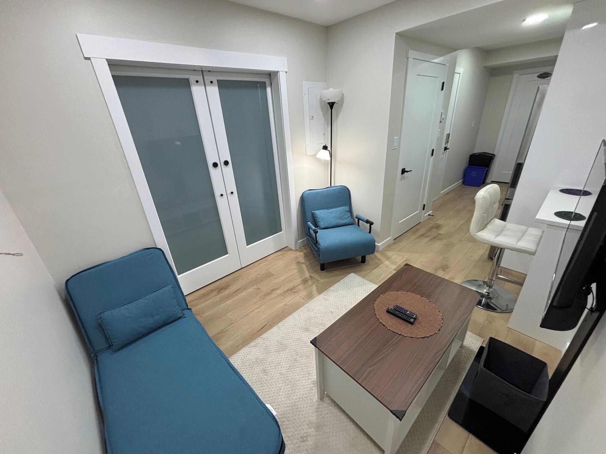 A modern living room with a sofa, a coffee table, and a blue armchair.
