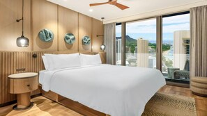 Ein Hotelzimmer mit einem großen Bett, Holzwandverkleidung, Blick auf die Stadt und einem Deckenventilator.