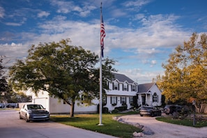 A residential area with a flagpole, a house, and parked cars. - Location, Location, Location (Sandy)