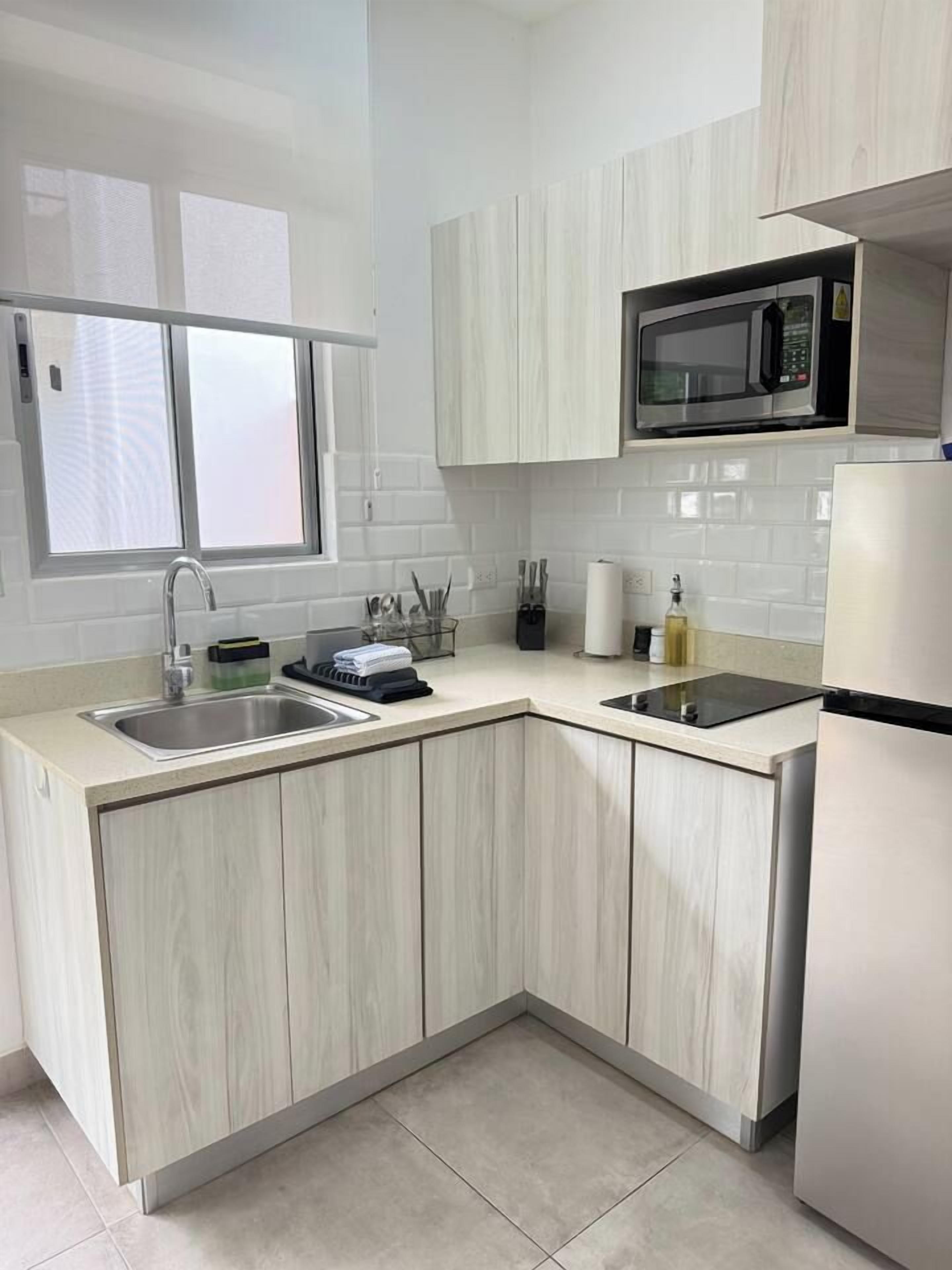 A modern kitchen with a built-in microwave, two sinks, and a window above the sink.