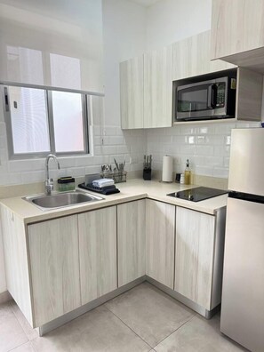 A modern kitchen with a built-in microwave, two sinks, and a window above the sink. - Drift Studio at Costa Lofts - Modern Boho Escape - Apartment (Jaco)