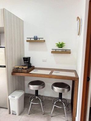 A compact kitchenette with a coffee maker, two stools, and a small trash bin. - Drift Studio at Costa Lofts - Modern Boho Escape - Apartment (Jaco)