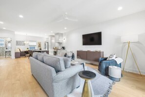 A modern living room with a grey sofa, a coffee table, and a TV mounted on the wall. - 2 Homes Sleeps 18 with 6 Bedrooms, Rooftops + Garage (Nashville)