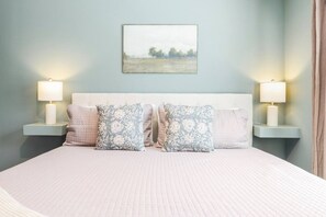 A bed with a white headboard, two bedside lamps, and patterned pillows. - 2 Homes Sleeps 18 with 6 Bedrooms, Rooftops + Garage (Nashville)