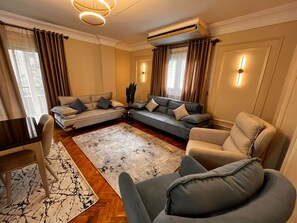 Ein Wohnzimmer mit einer Couch, Sesseln, einem Couchtisch und einem Teppich.