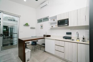 A modern kitchen with a central island, a microwave, and a sink. - Casa Swell at Costa Lofts (Jaco)