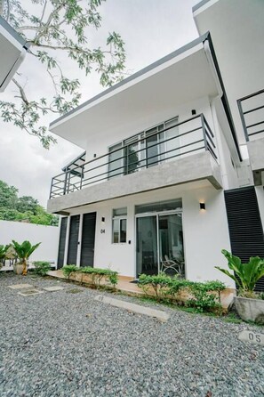 A modern two-story house with a balcony, a driveway, and a number '04' sign. - Casa Swell at Costa Lofts (Jaco)