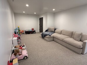 Una sala de estar con un sofá seccional color beige, una mesita y un coche de juguete.