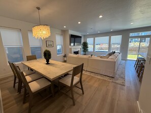 A modern kitchen with a dining table, chairs, and a chandelier. - Mountain Green Getaway - Home Theater Room - Backyard Hot tub and Firepit (Mountain Green)