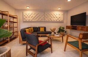 A modern living room with a sectional sofa, a coffee table, and a TV mounted on the wall. - Casa Aurelia | Cozy Stay with AC and Parking (Oaxaca de Juárez)