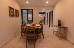 A modern dining area with a wooden table set for four, flanked by chairs with cushioned seats. - Casa Aurelia | Cozy Stay with AC and Parking (Oaxaca de Juárez)
