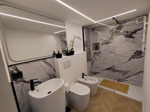 A modern bathroom with a marble backsplash, a large mirror, a bidet, and a toilet. - Naumachia77 In the heart of Catania’s historic center, where nightlife meets culture. (Catania)
