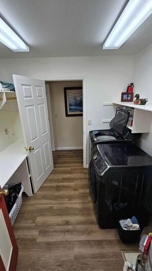 A laundry room with a washing machine, dryer, and a shelf with items. - The Ranch Near the River- Hot tub -outdoor dining (Nevada City)