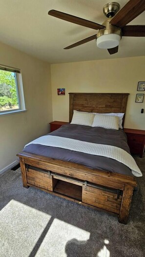 A bedroom with a wooden bed, a ceiling fan, and a window. - The Ranch Near the River- Hot tub -outdoor dining (Nevada City)