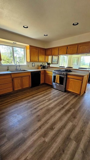 A kitchen with wooden cabinets, a dishwasher, an oven, and a sink. - The Ranch Near the River- Hot tub -outdoor dining (Nevada City)