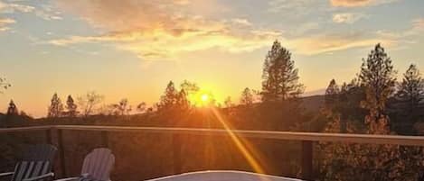 Boblebad med udsigt til solnedgang og træer i baggrunden.