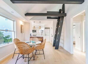 Una cocina moderna con una isla central, muebles blancos e iluminación colgante.