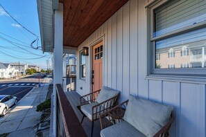 A porch with wicker chairs and a stop sign visible on the street. - 3BR Beach House Near Ocean City Boardwalk (Ocean City)