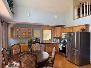 A kitchen with wooden cabinets, a stainless steel refrigerator, and a dining table with chairs. - 3-bedroom Chalet with fantastic Long range Mountain Views, HOT TUB and Sauna (Franklin)