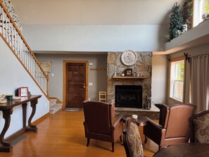 A living room with a fireplace, wooden flooring, and a staircase. - 3-bedroom Chalet with fantastic Long range Mountain Views, HOT TUB and Sauna (Franklin)
