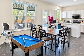 A kitchen with a pool table, dining area, and a view of the outside. - Beach-Entry Pool Mini-Golf FirePit SeaWorld & BMT (San Antonio)